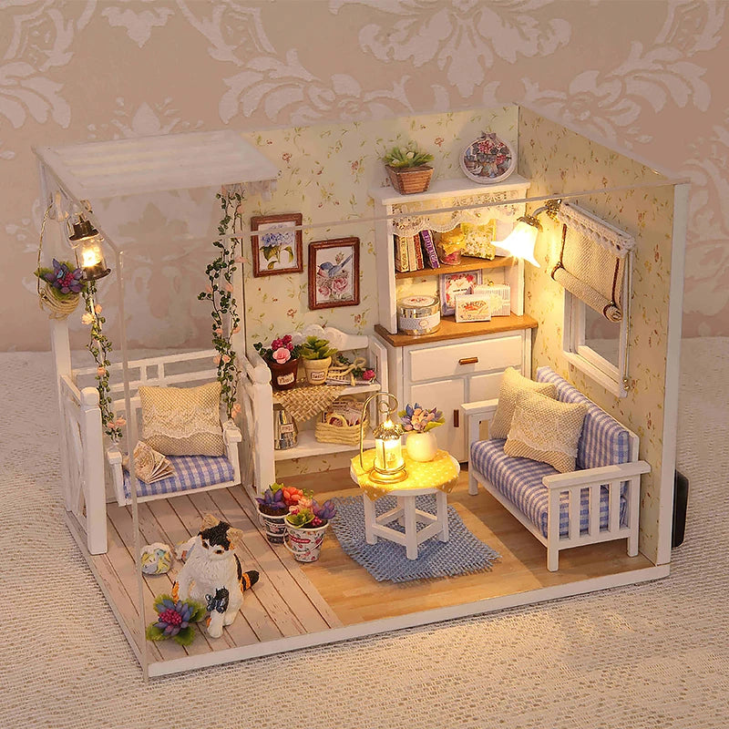 A miniature dollhouse kit featuring white furniture, decor, and a kitten figure set within a light-colored room scene.