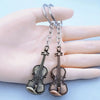 Silver vintage violin keychain hanging from a hand.