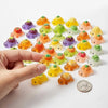A hand holds a collection of mini glow-in-the-dark turtle resin figurines in various colors on a white background.