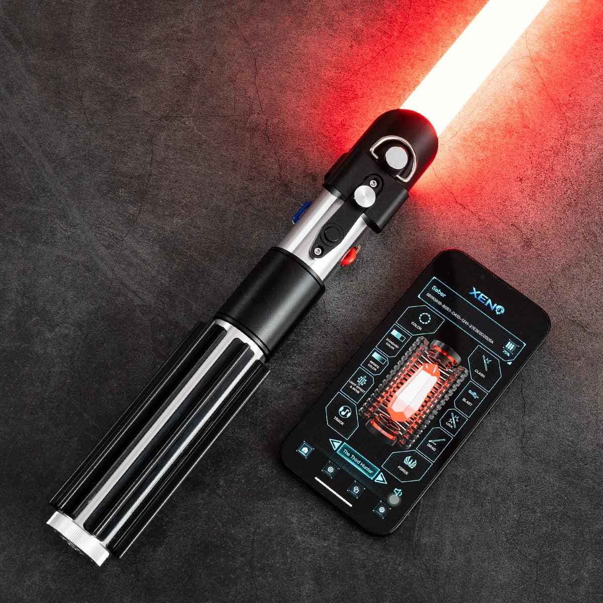 A black lightsaber with a glowing red blade and a smartphone displaying control features is shown on a dark surface.