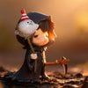 A collectible figure of a dark-haired monster with a white, conical hat and a knife, set against a warm, golden background.