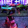 A close-up shot of a blue 1:64 scale remote control off-road truck with bright orange lights on a dark surface.