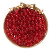 A round gold-rimmed dish filled with bright red glass crackle beads for jewelry making