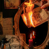 A hand holds a piece of aged paper with a flame burning through it, set against a dark background with decorative elements.