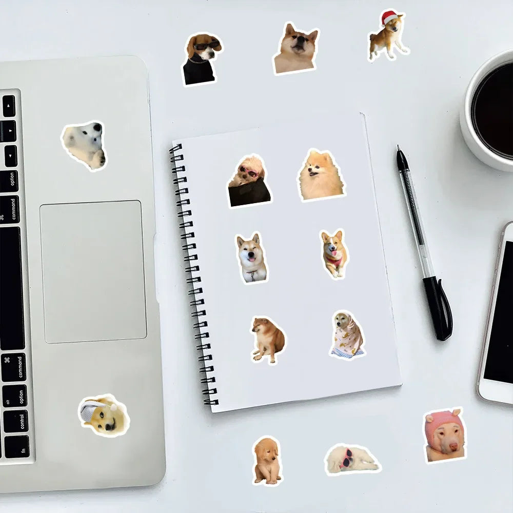 A spiral notebook filled with various funny dog stickers placed on a white desk next to a silver laptop.