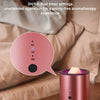 A pink electric wax melt heater is shown on a wooden surface next to a blurred background of bedding.