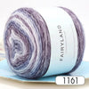 A ball of silky gradient yarn in shades of purple and gray resting on a light blue surface.