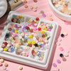 A white tray filled with various colored glass spacer beads, including jade tones, scattered on a pink surface.