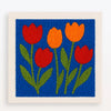 Punch needle embroidery kit featuring red and orange tulip flowers on a blue background