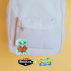 A light pink backpack with a pocket featuring a green plush monster keychain.