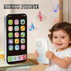 A baby is holding a white interactive learning phone toy with music and stories displayed on the screen.