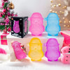 A collection of pink, purple, and blue squishy toys shaped like Santa figures and snowmen on a white surface.