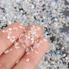 A hand holds crushed clear and pinkish crystals for resin and jewelry making