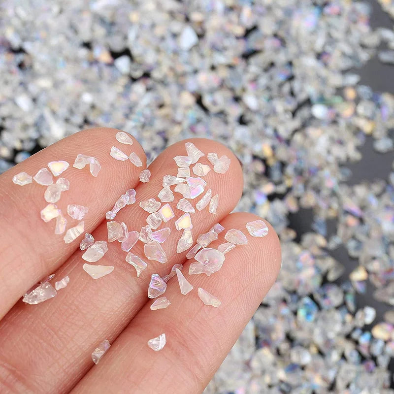 A hand holds crushed clear and pinkish crystals for resin and jewelry making