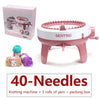 A pink hand-operated knitting machine with needles and yarn rolls is shown next to its packaging box.