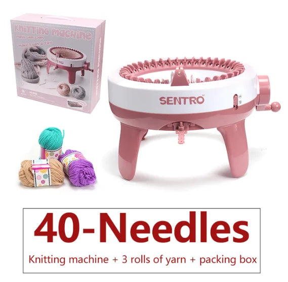 A pink hand-operated knitting machine with needles and yarn rolls is shown next to its packaging box.