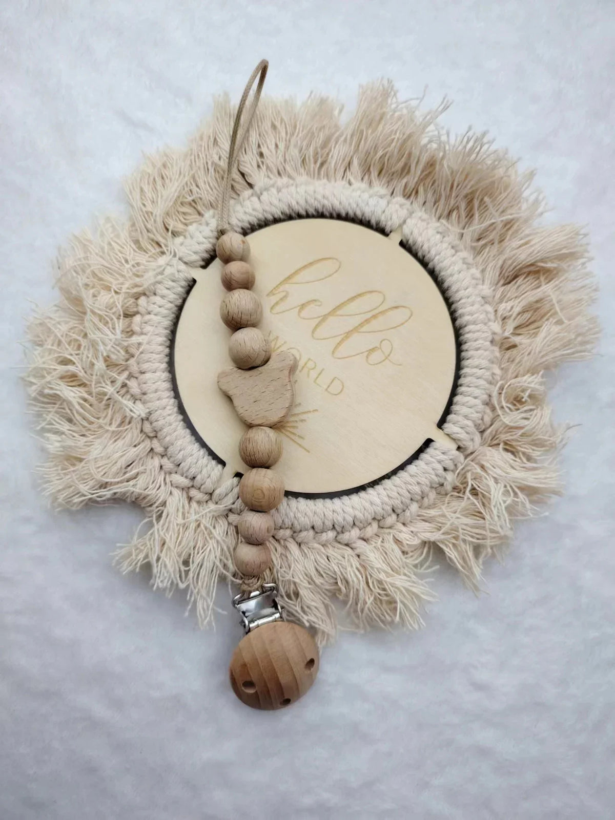 A personalized wooden baby pacifier clip featuring silicone beads and a feather-like natural fiber wreath.