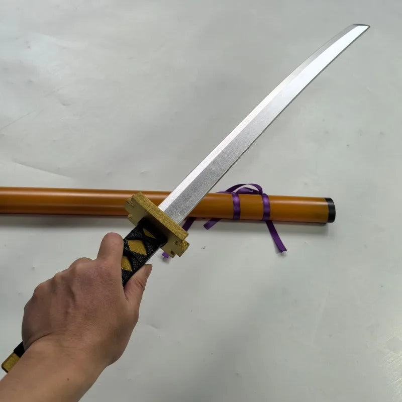 A hand holds a silver katana prop with a wooden hilt and purple cord, resting on an orange stick.