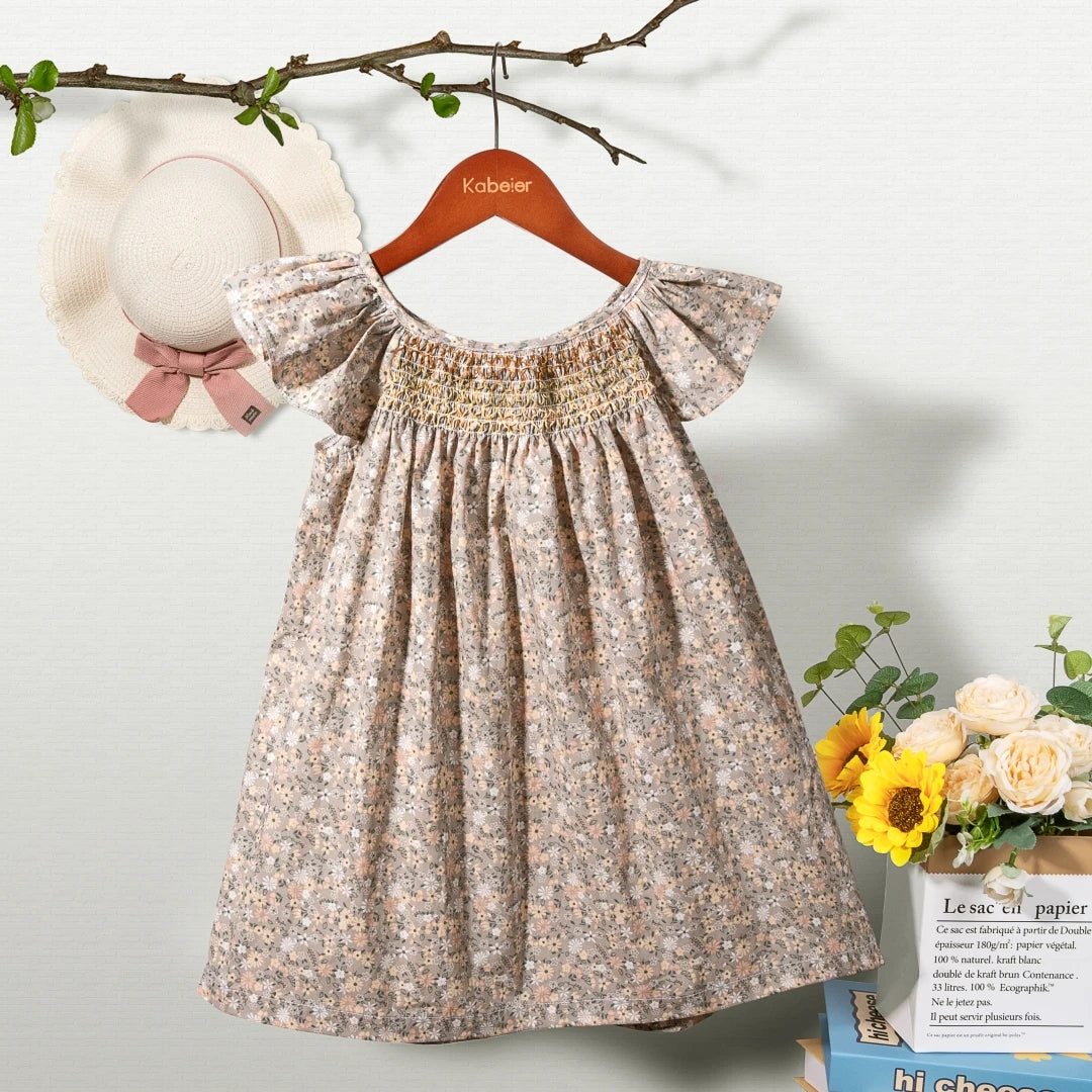 A beige floral smocked summer dress for girls with puff sleeves hanging on a wooden hanger.