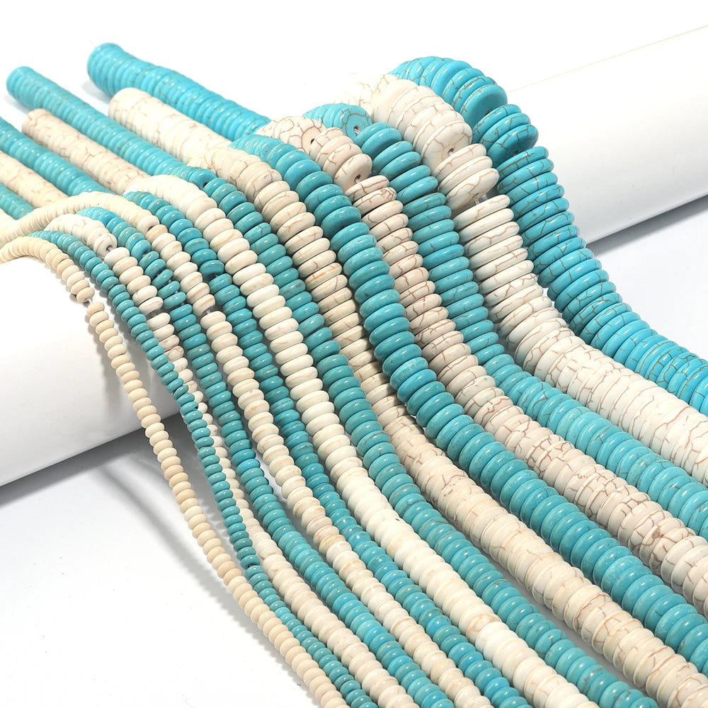 A close-up of numerous strands of natural turquoise stone beads in shades of blue and white, laid out on a white surface.