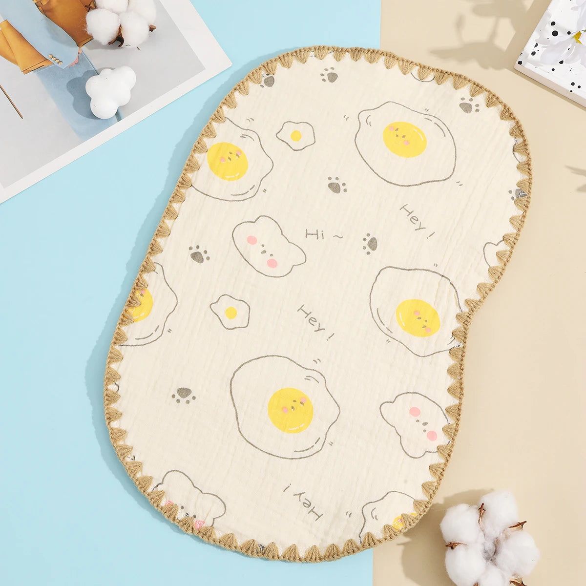 A beige embroidered flat pillow with a scalloped edge featuring yellow and white egg patterns on a light blue background.