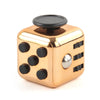 A gold-colored fidget cube with black buttons and a silver accent, shown from above.