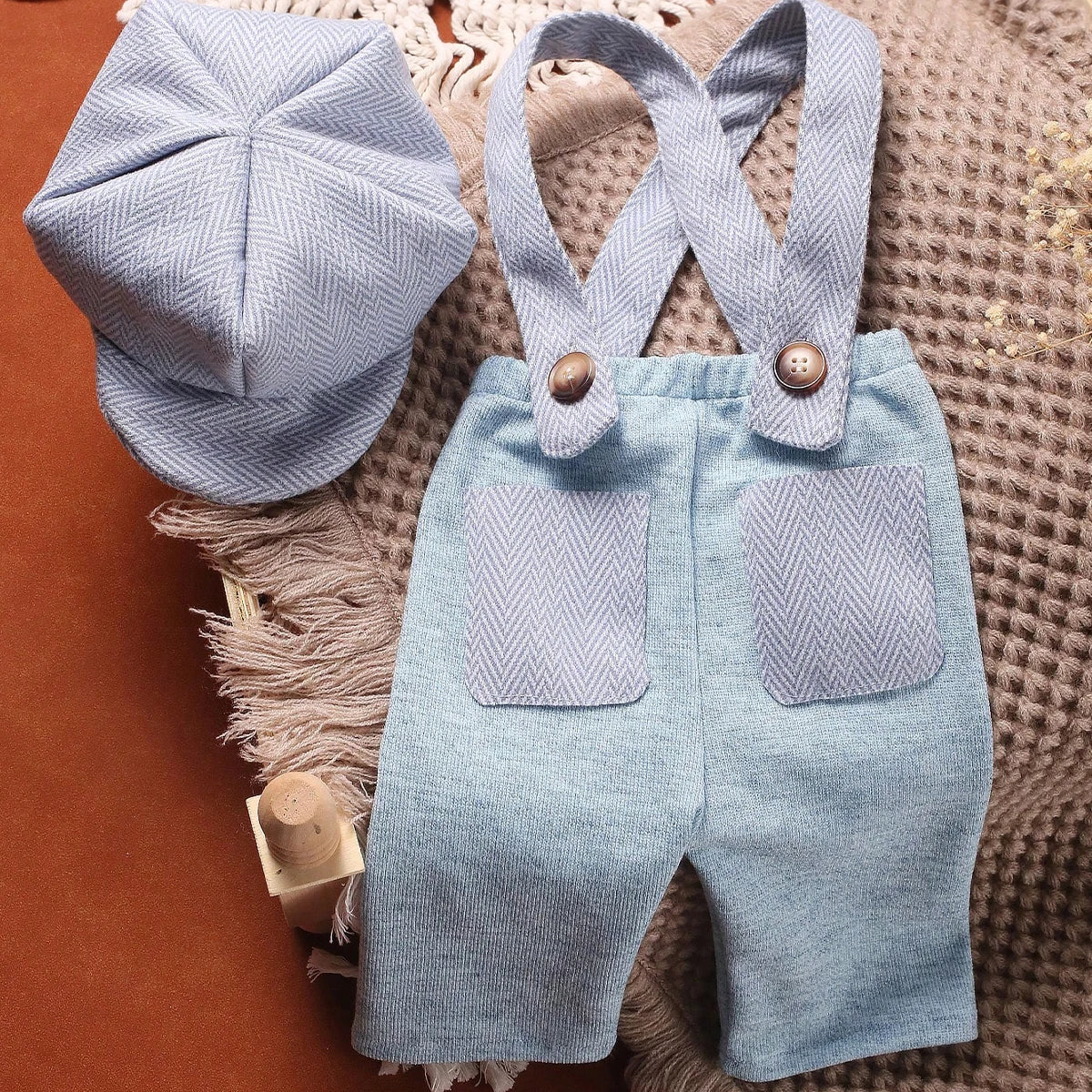 A light blue knit romper and matching newsboy cap set for a newborn boy.