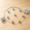A black circle drawn on a wooden surface with several black and white soccer balls arranged around it.