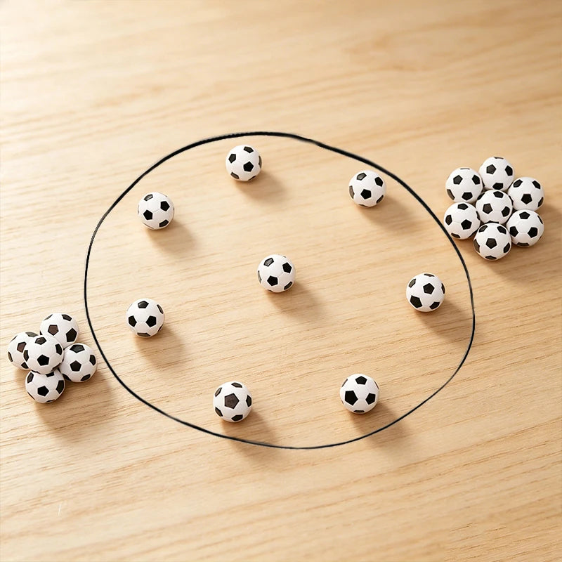 A black circle drawn on a wooden surface with several black and white soccer balls arranged around it.