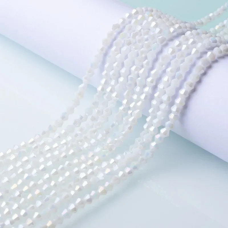 A close-up of white faceted glass crystal beads strung together, draped over a white cylindrical object.