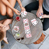 A close-up shot of hands playing with a pile of red and black playing cards on a wooden table.