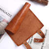 A brown PU leather storage bag designed to hold dice, shown next to a magazine.