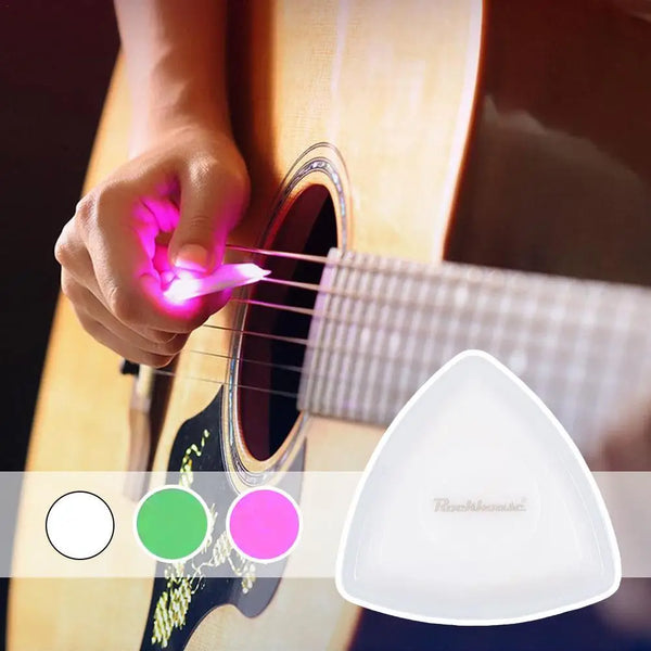 A hand is using an LED glowing guitar pick on a wooden acoustic guitar.