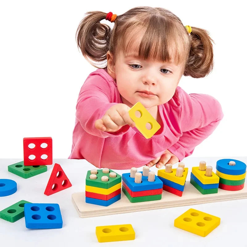 A toddler is holding a yellow wooden geometric shape puzzle piece while surrounded by various colored wooden shapes.