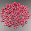 A pile of 20 small, shiny red acrylic bow beads for jewelry making.