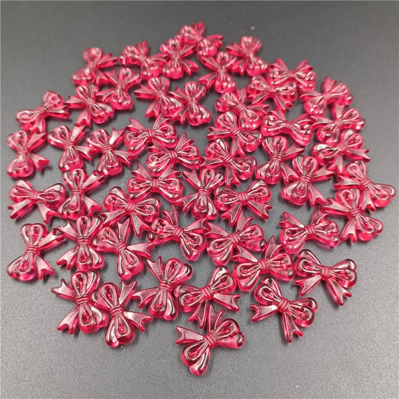 A pile of 20 small, shiny red acrylic bow beads for jewelry making.