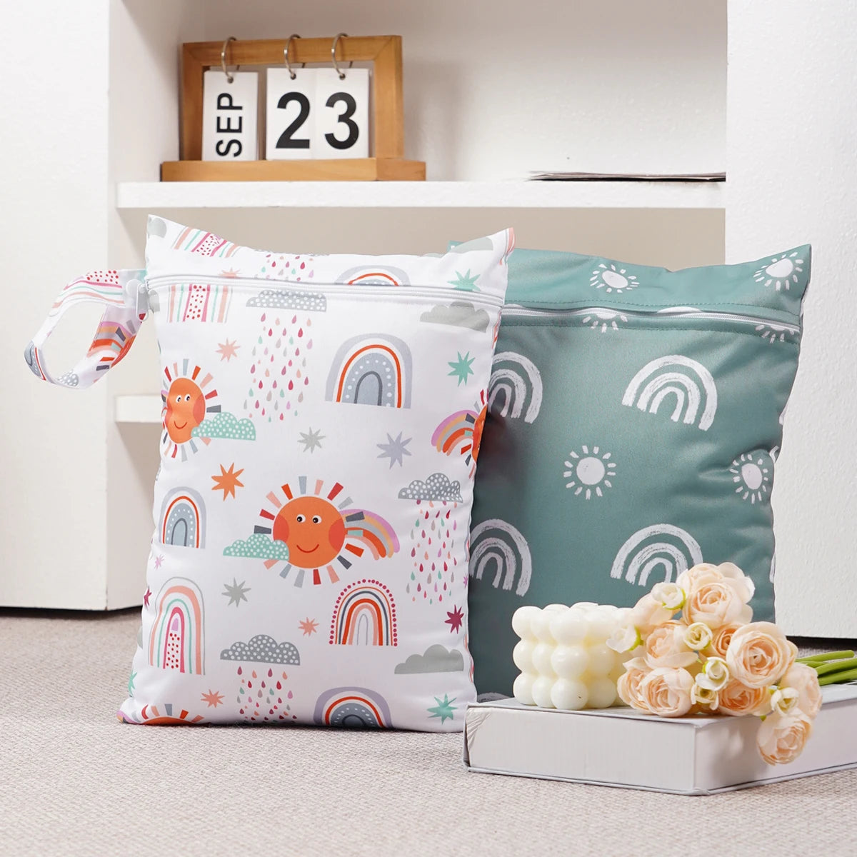 A set of two reusable waterproof baby wet bags featuring colorful rainbows and suns on a light background.