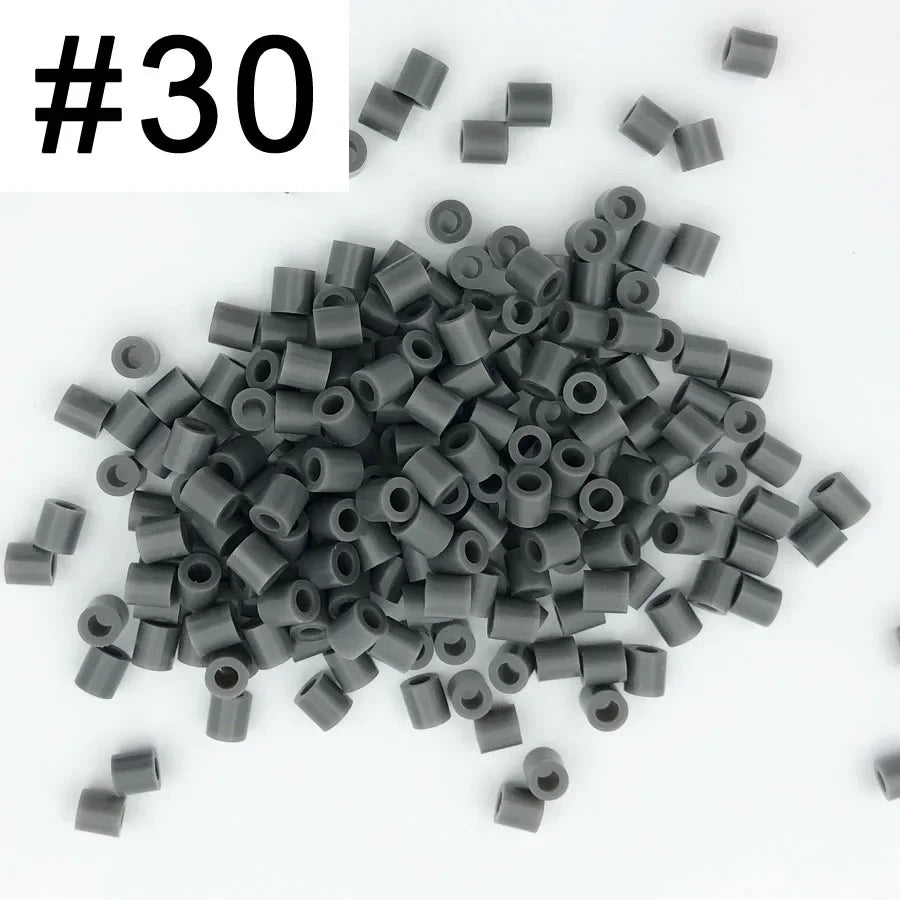 A pile of 1000 small, cylindrical fuse beads in assorted dark gray and black colors.