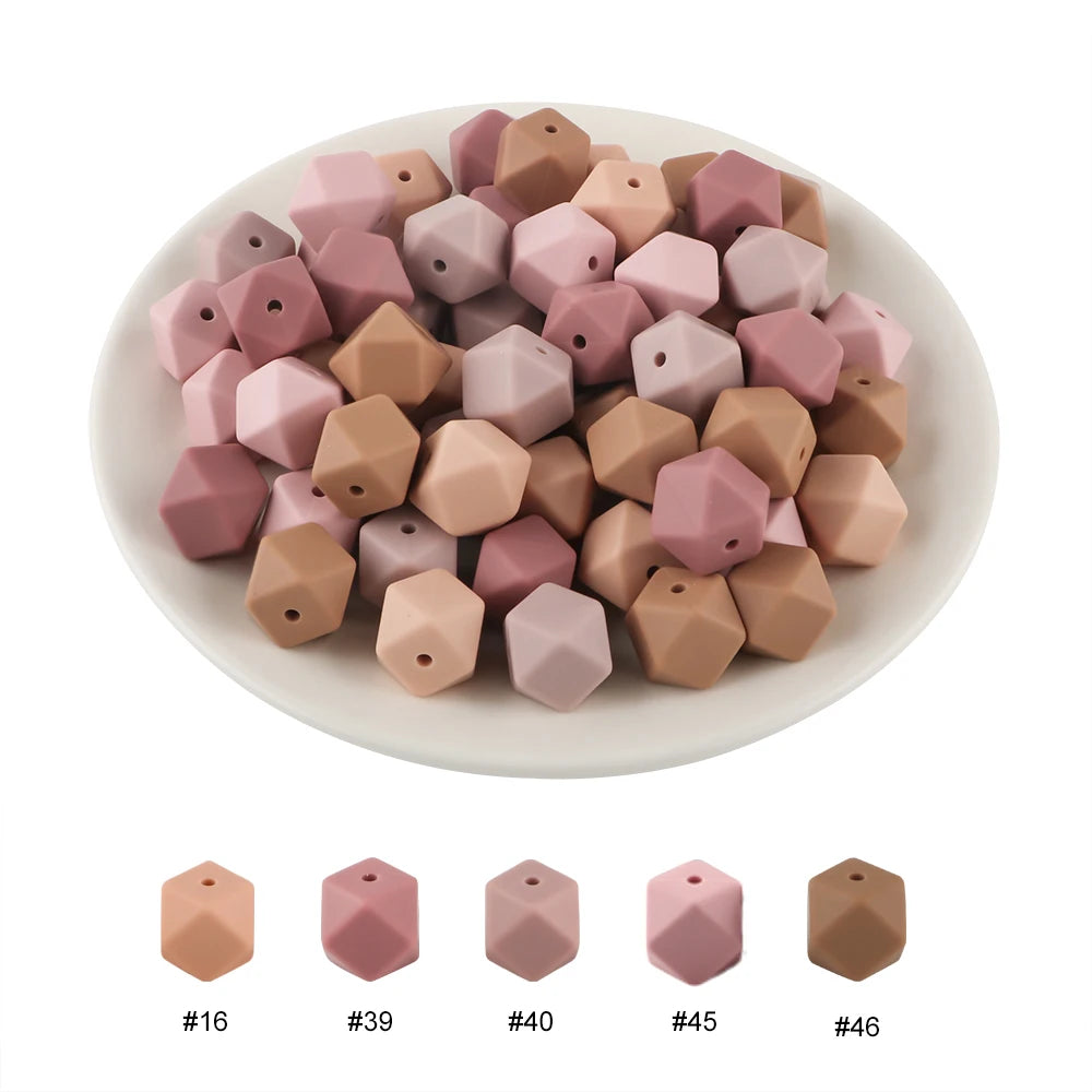 A collection of 15 hexagonal silicone beads in various dusty rose and nude shades arranged on a white plate.