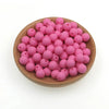 A wooden bowl filled with numerous small, round pink silicone beads for jewelry making and crafts.