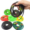 A hand is holding a coiled rubber snake toy in various colors including black, green, red, and yellow.