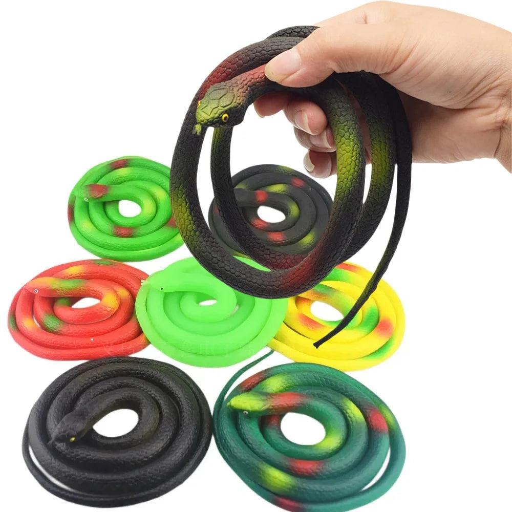 A hand is holding a coiled rubber snake toy in various colors including black, green, red, and yellow.
