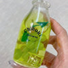 A hand holds a clear bottle filled with green squishy milk cup toys labeled Chiboki.