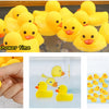 A set of yellow rubber ducks floating in water and a hand holding one duck.
