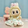 A light yellow plush doll wearing a white ruffled dress and pink flower accessory.