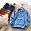 Light blue kids cartoon bear pullover sweatshirt displayed on a hanger with other clothing items.