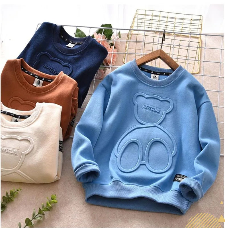 Light blue kids cartoon bear pullover sweatshirt displayed on a hanger with other clothing items.