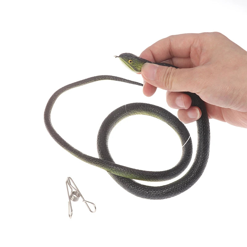 A hand holds a realistic green snake prank toy with a string and clip.