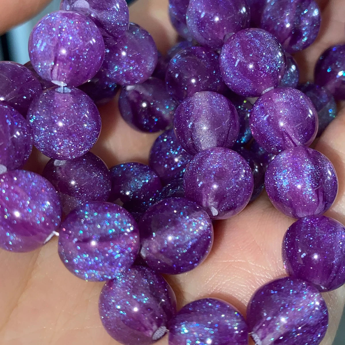 A collection of purple resin spacer beads with a starry sky effect for jewelry making