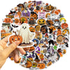 A hand holds a large collection of Halloween-themed waterproof stickers for laptops and bottles.